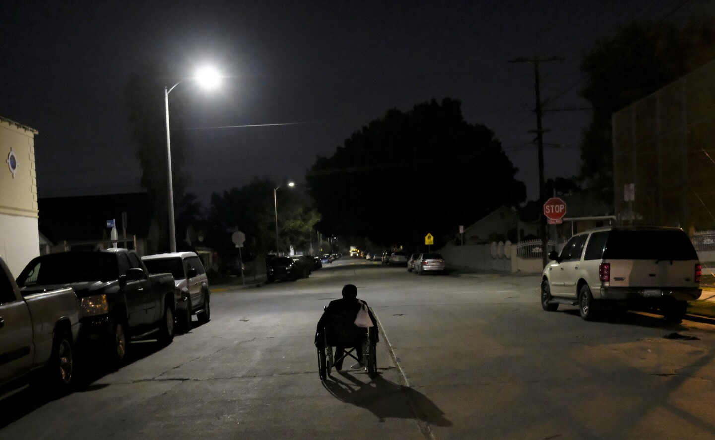A woman pushes her wheelchair at night near South Hoover Street and West Florence Avenue in South Los Angeles. She was counted by volunteers in homeless count in South L.A.