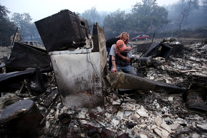 YREKA, CALIF. - AUG. 1 , 2022. Sheri Marchetti-Perrault and James Benton embrace as they sift through the remains of their home, which was destroyed by the McKinley fire as it burned along Highway 96 near Yreka over the weekend. The fire has charred about 51,000 acres and destroyed dozens of homes and structures. (Luis Sinco / Los Angeles Times)
