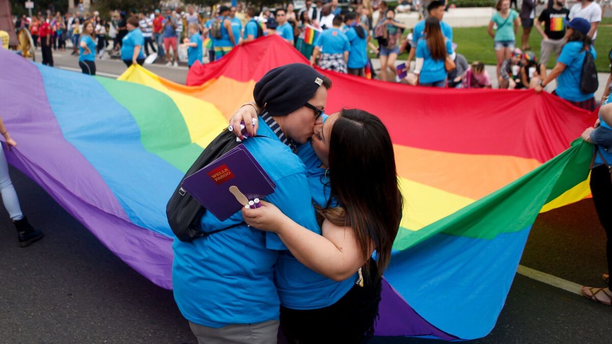 Couple Lulu Garcia and Dani Garcia kiss during the annual LA Pride Parade in West Hollywood. This was their first pride parade. (Harrison Hill / Los Angeles Times)
