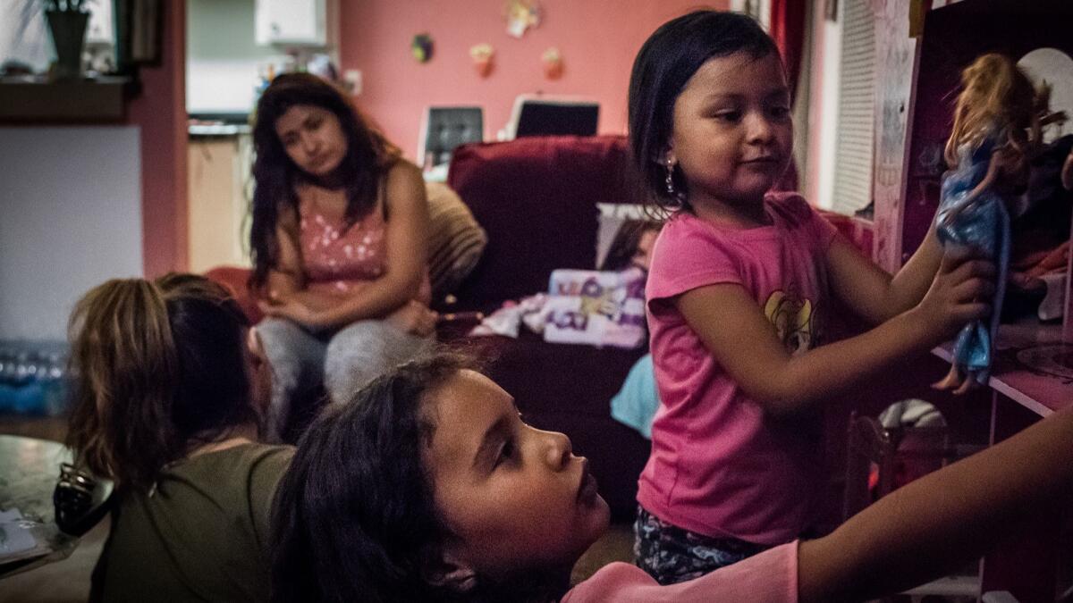 Marley, center, and her friend Kati play with a dollhouse while their mothers talk.