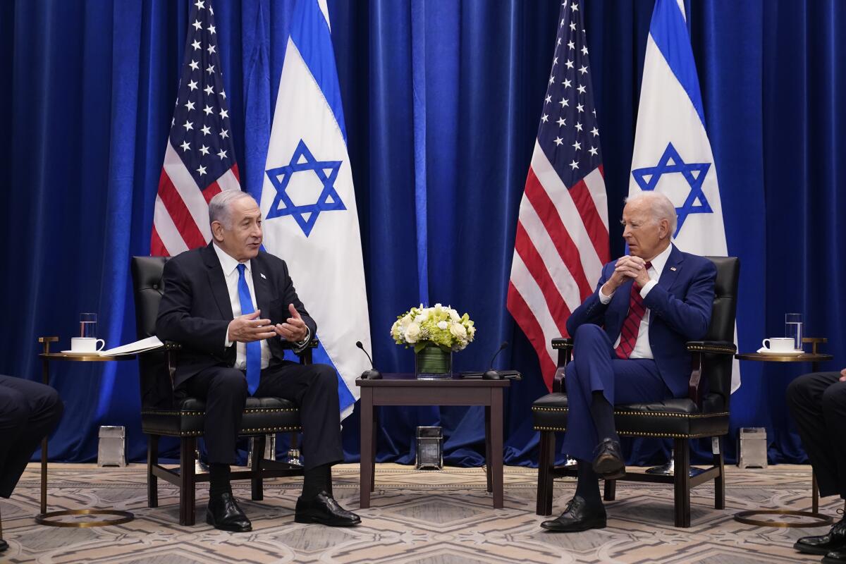 Israeli Prime Minister Benjamin Netanyahu and President Biden sit in front of dark blue curtains and U.S. and Israeli flags 