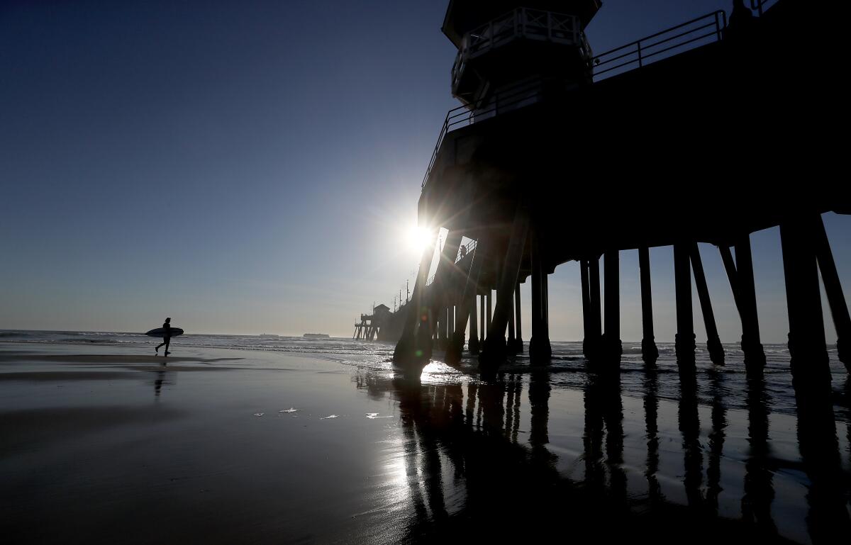  A surfer catches the last waves of the year in Huntington Beach on Dec. 31, 2020. 