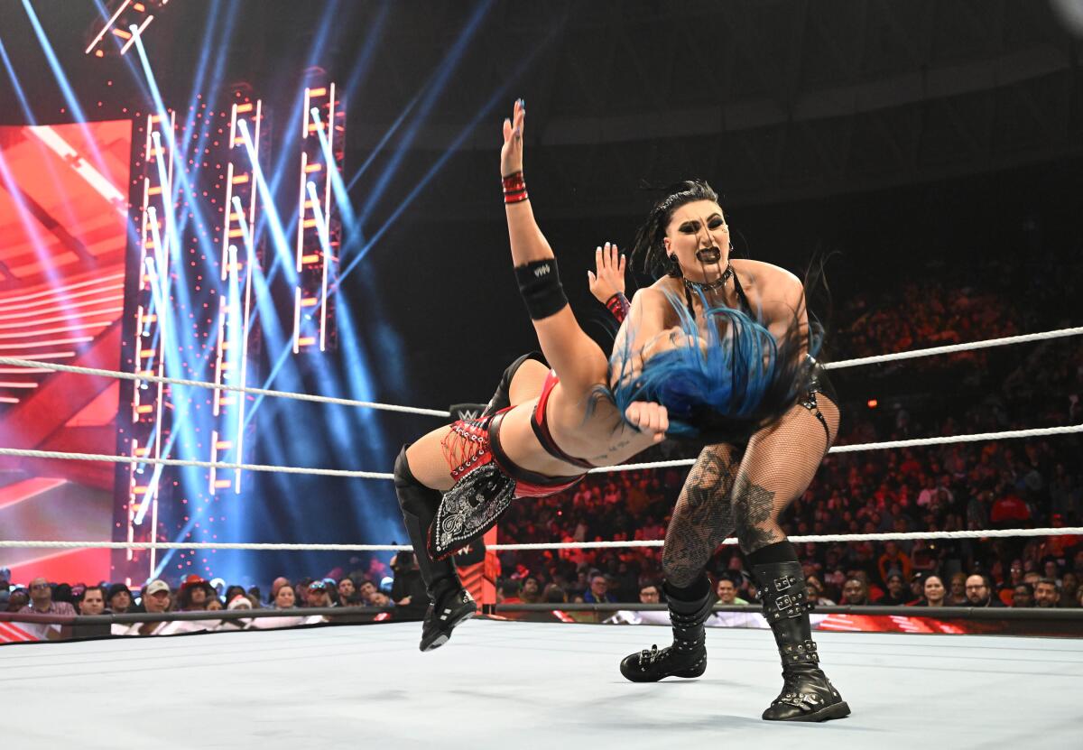 One woman slams another onto the wrestling ring floor.