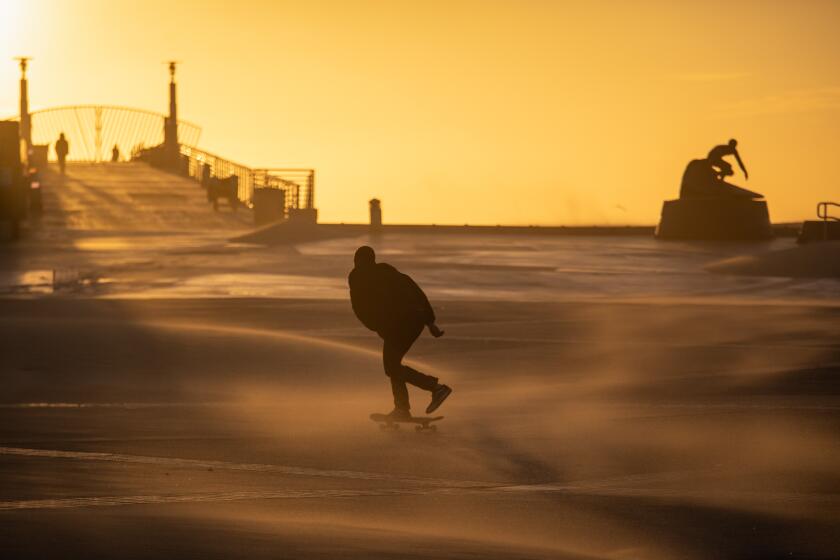 Hermosa Beach, CA - February 22: A skater battles wind and sand, while crossing Pier Plaza, in Hermosa Beach, CA, Wednesday, Feb. 22, 2023. (Jay L. Clendenin / Los Angeles Times)