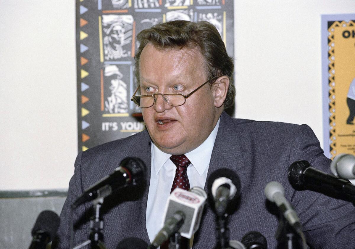 Martti Ahtisaari in a suit in front of a bank of microphones