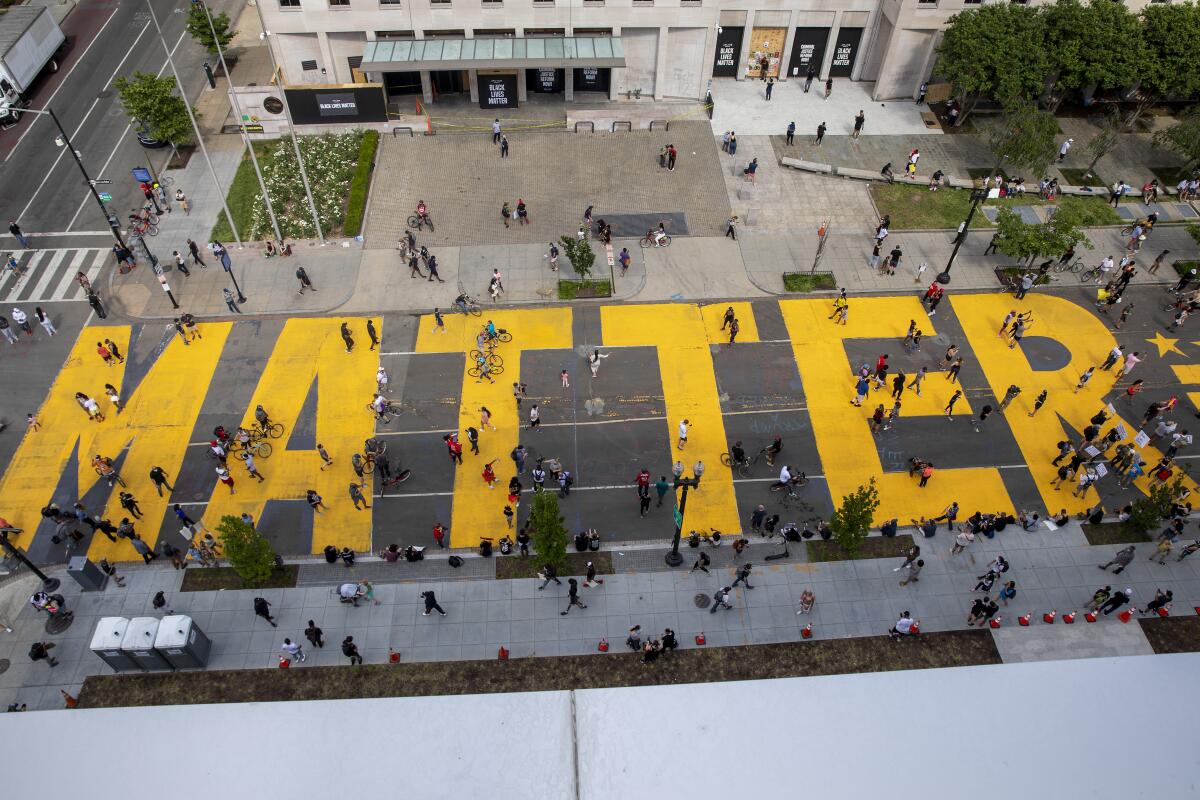 People walk down 16th street in Washington, D.C., which is painted with huge letters spelling "Black Lives Matter" 