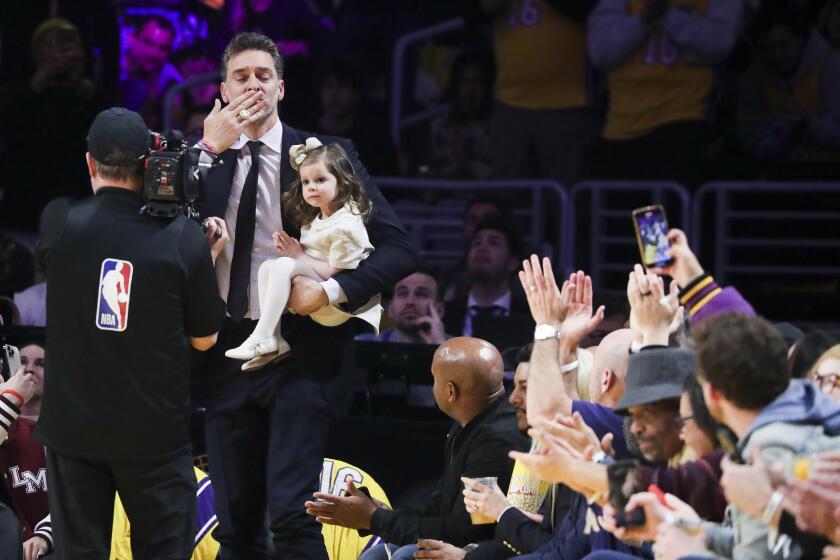 LOS ANGELES, CALIF. - MAR. 7, 2023. Former Los Angeles Lakers Pau Gasol blows a kiss to the fans while holding onto his daughter Elisabet Gianna Gasol as he makes his way on the court during the game against the Memphis Grizzlies in an NBA game at Crypto.com Arena in Los Angeles on Tuesday, Mar. 7, 2023. (Luis Sinco / Los Angeles Times)