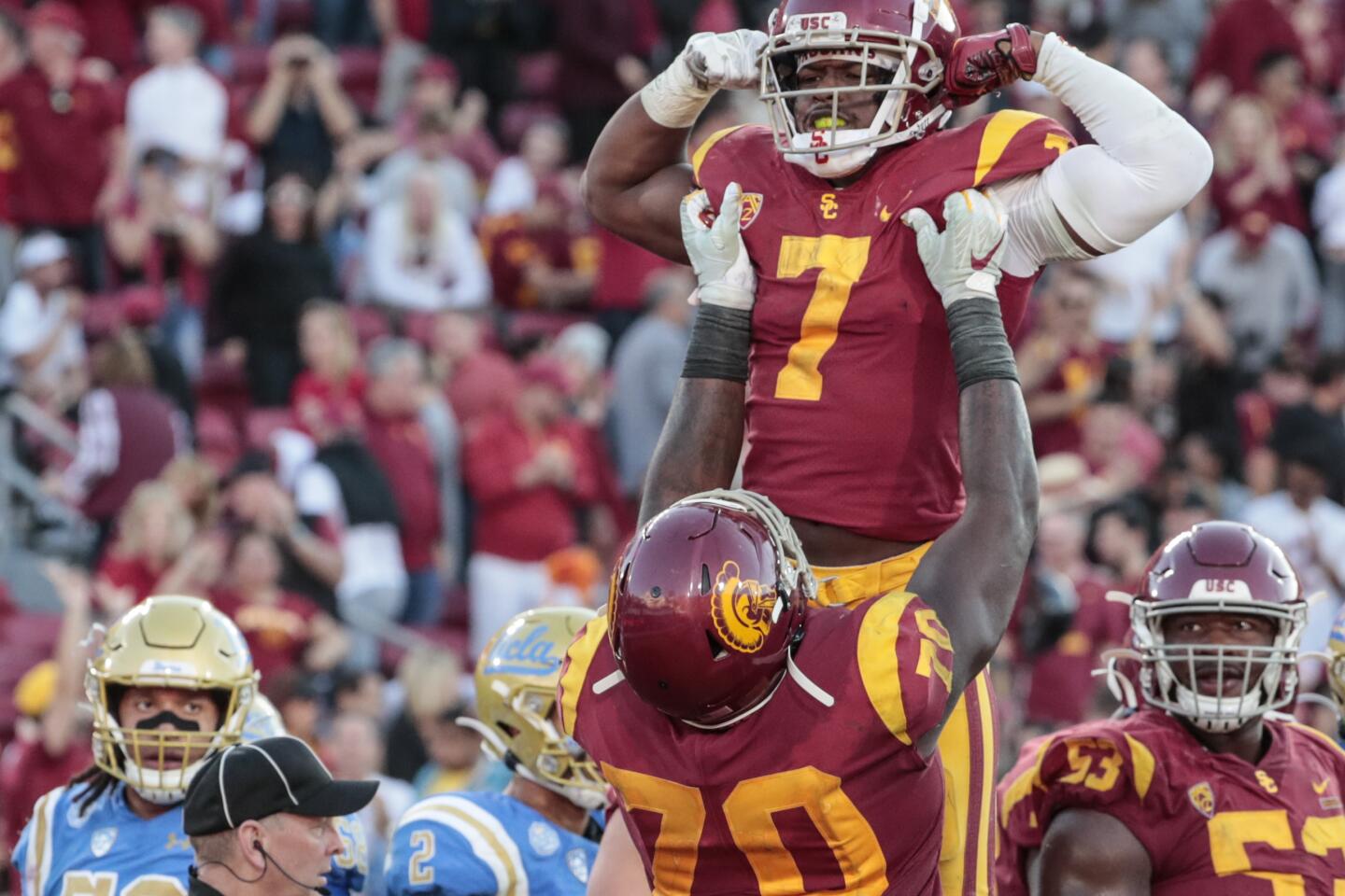 USC offensive tackle Jalen McKenzie (70) lifts running back Stephen Carr (7) after scoring a fourth quarter touchdown at the Coliseum on Saturday.