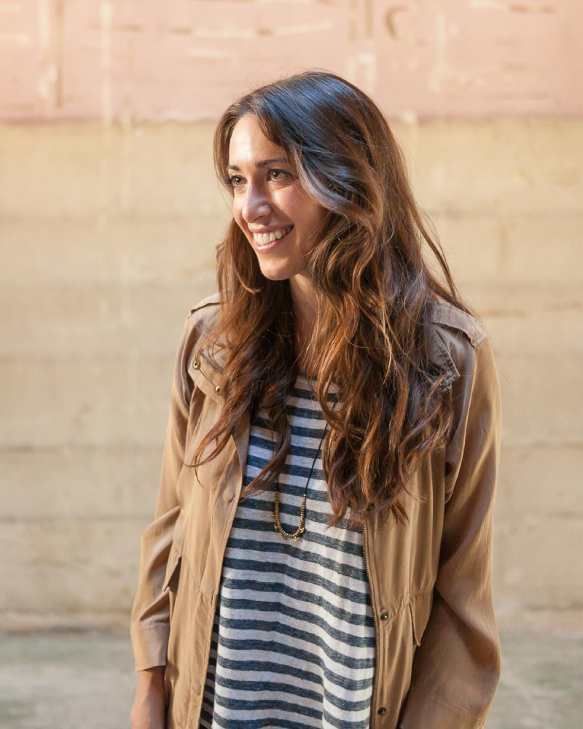 A portrait of Heather Sperling in a striped shirt and brown jacket