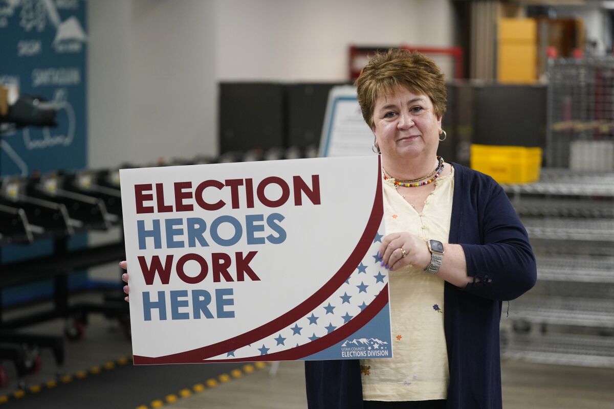 A woman holds an "Election Heroes Work Here" sign