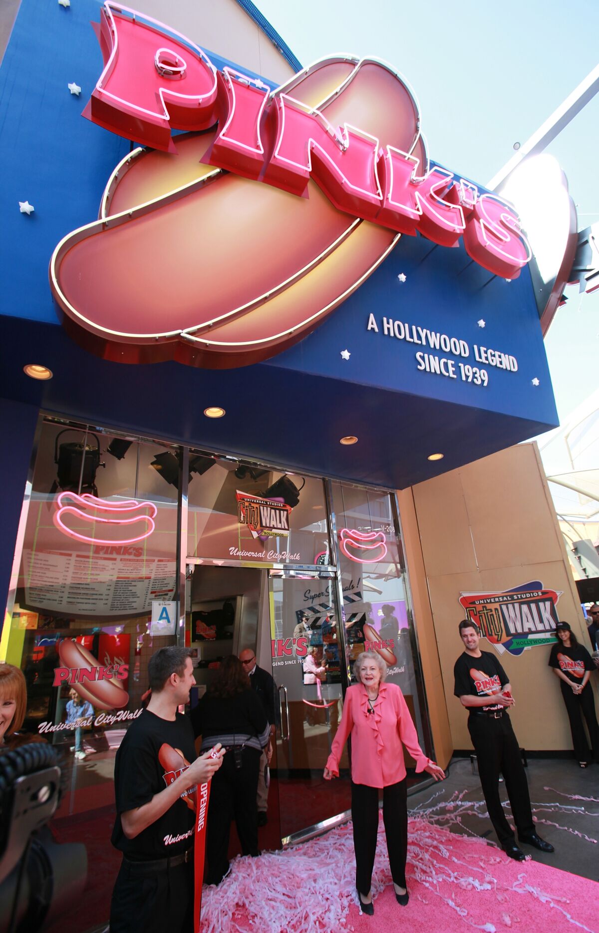 A woman in pink attends the grand opening of a restaurant