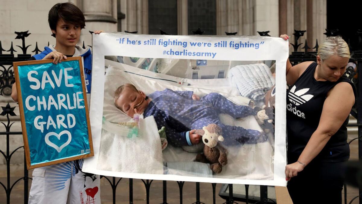 Supporters of critically ill baby Charlie Gard hold up a photograph of him outside the High Court in London where his case is being heard on July 14, 2017.