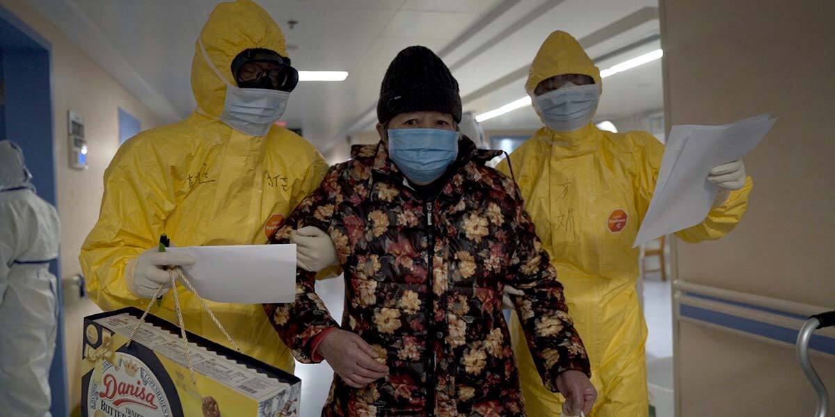 Two people in hazmat suits escort a patient in the documentary "76 Days."