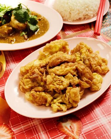 A fluffy Thai omelet, or kai jiew, in foreground, with shrimp in yellow curry and a mound of white rice behind it.