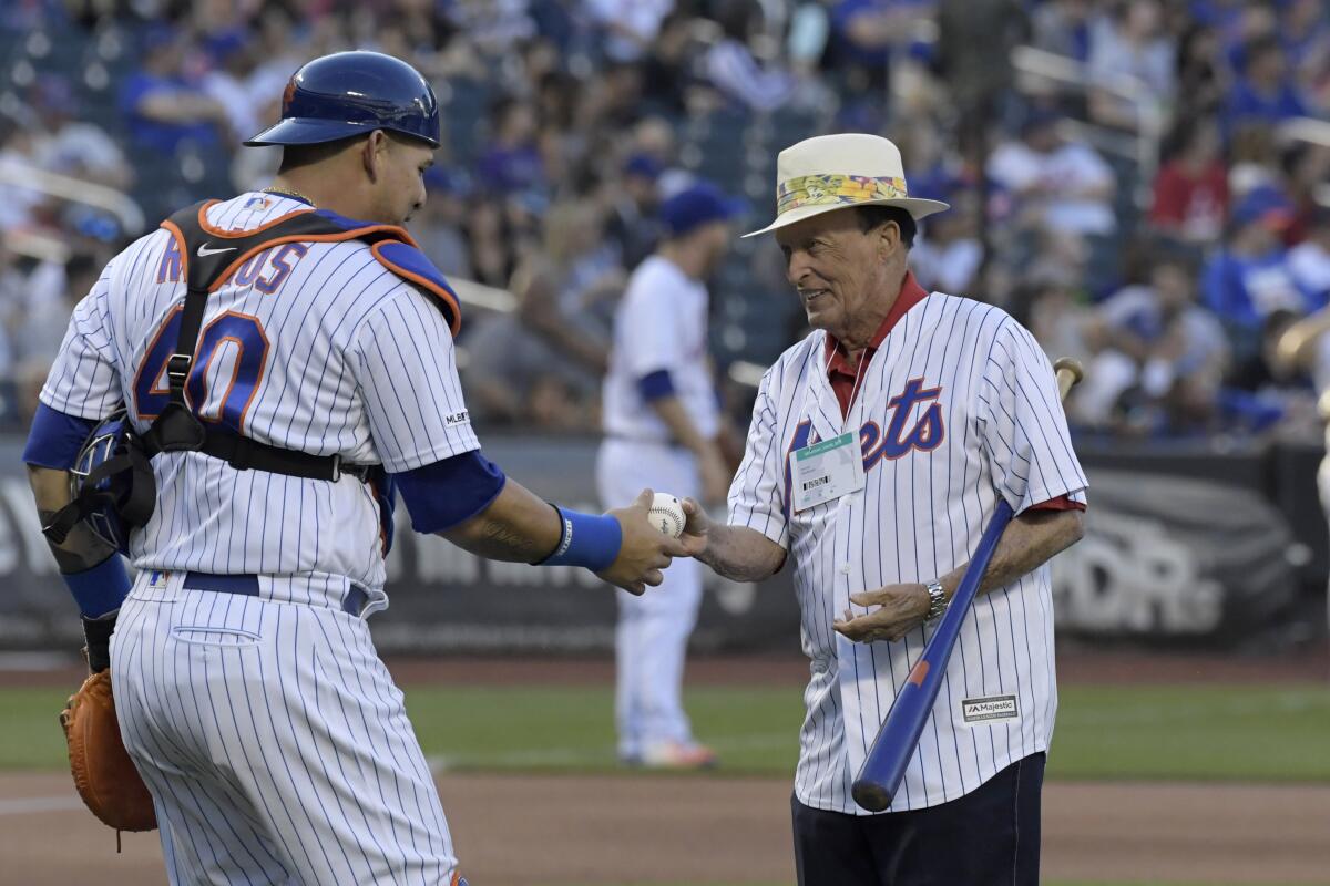 Former professional golfer Chi Chi Rodriguez gets the ball from New York Mets catcher Wilson Ramos 