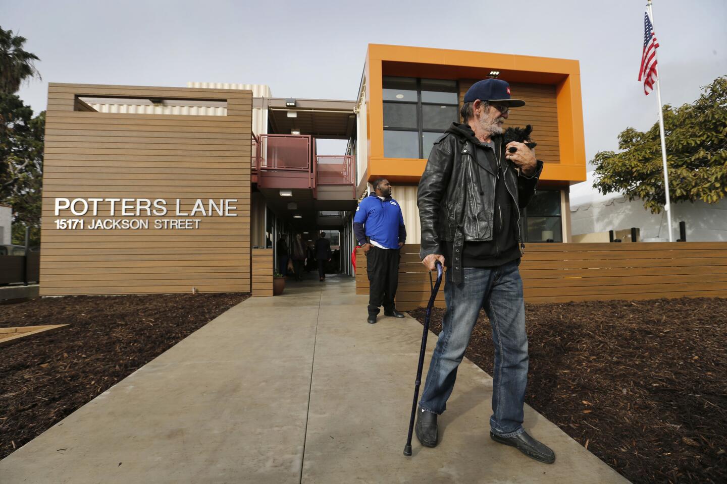 Homeless Army veteran Jimmy Palmiter, 59, holds his dog Fifi while touring his future home during the dedication of Potter's Lane, the state's first multifamily housing development built with recycled shipping containers.