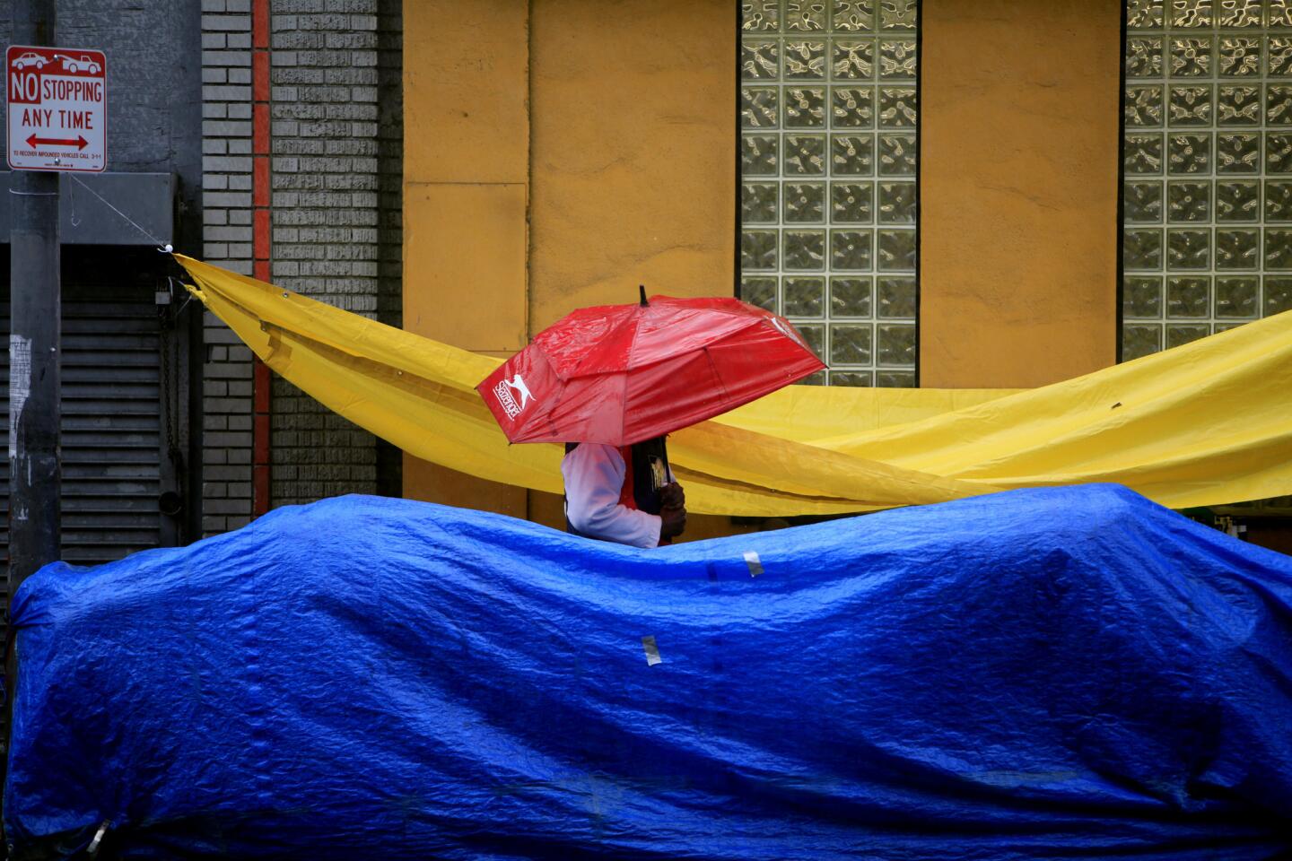 Homeless people try and keep their belongings dry in the rain on skid row in Los Angeles.