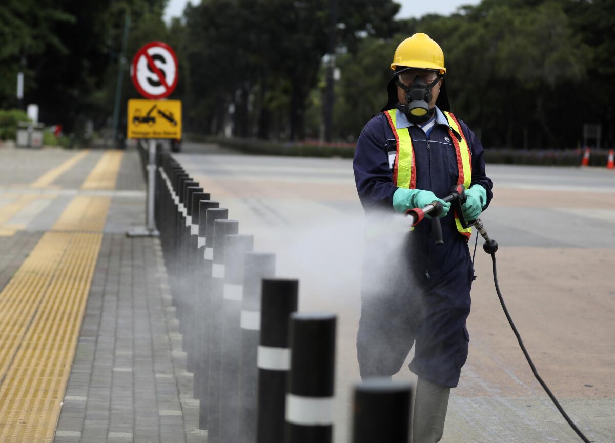 A worker sprays disinfectant at the pedestrian walkway at Senayan Sports Complex in Jakarta, Indonesia.