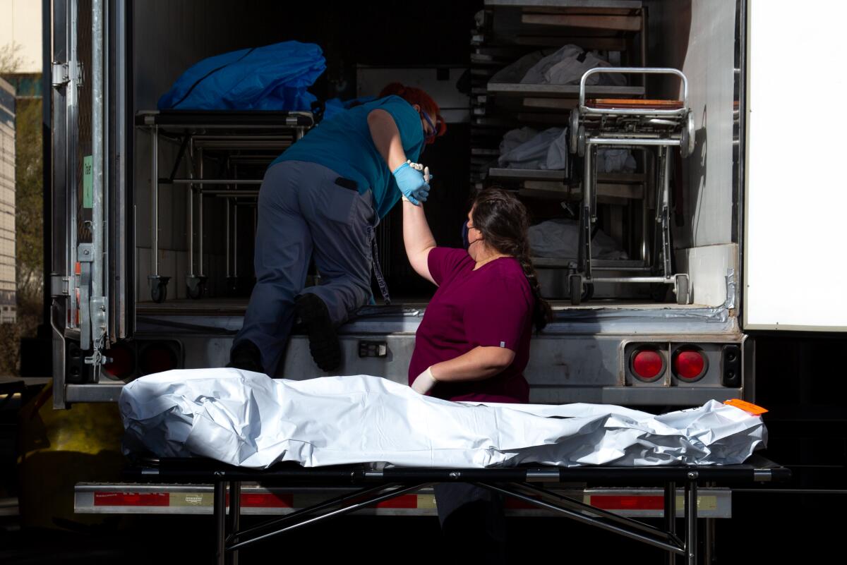 Employees prepare to move a body into a refrigerated semitruck at the Pima County medical examiner's office in Tucson.