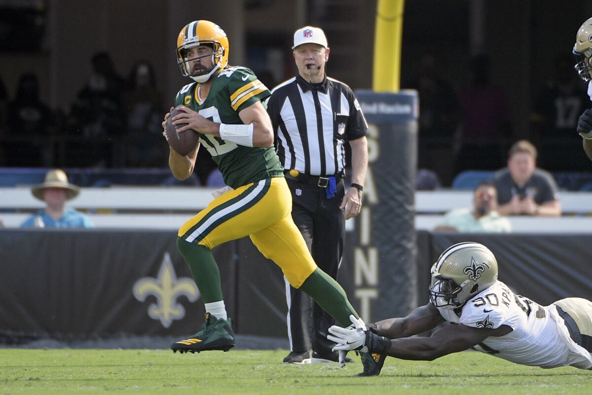 Green Bay Packers quarterback Aaron Rodgers, left, scrambles as he is pressured by New Orleans Saints linebacker Tanoh Kpassagnon during the first half of an NFL football game, Sunday, Sept. 12, 2021, in Jacksonville, Fla. (AP Photo/Phelan M. Ebenhack)