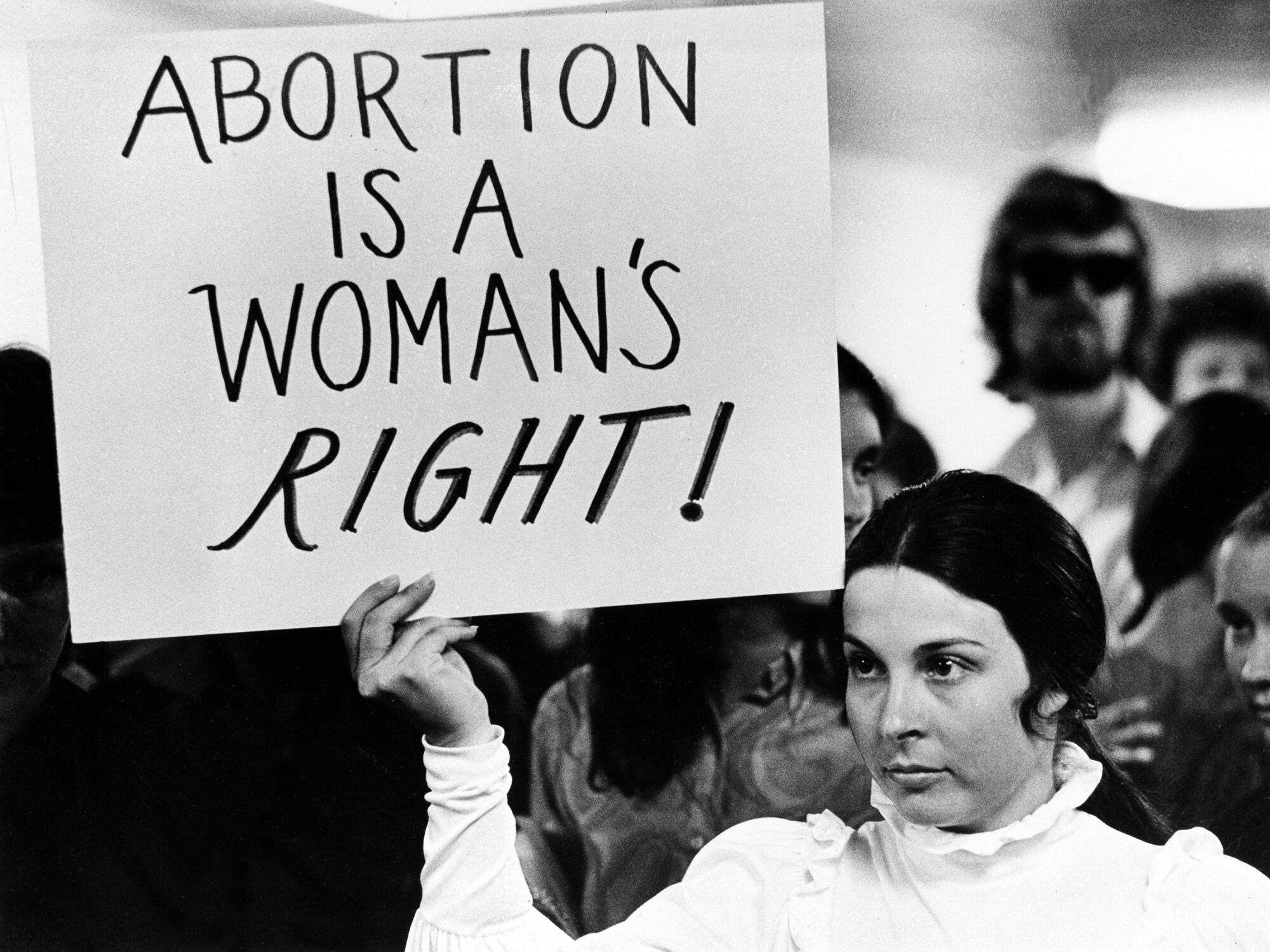 1971 photo of a young woman holding a sign demanding a woman's right to abortion