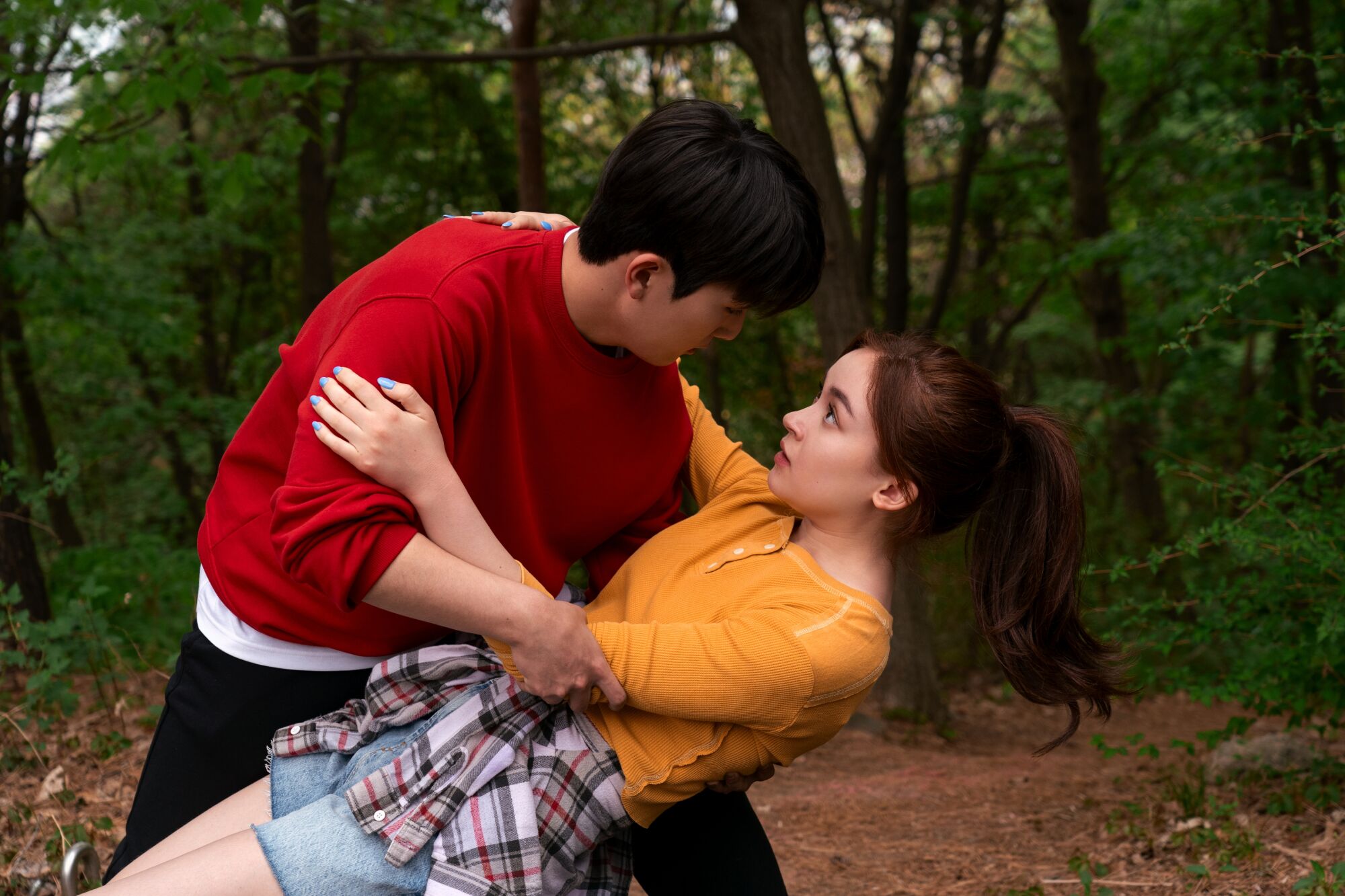 a boy in a red shirt dances with and dips a girl in an orange shirt