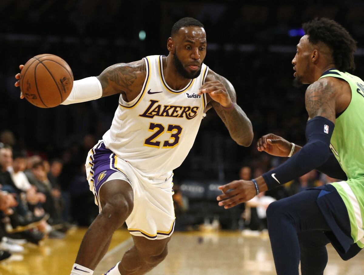 Lakers star LeBron James drives around Minnesota Timberwolves forward Robert Covington during the second half of the Lakers' 142-125 win Sunday.