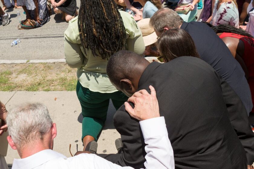 Charleston residents bow in prayer during a vigil for the nine victims of a mass shooting in the Emanuel African Methodist Episcopalian Church in Charleston, S.C. Police arrested a lone gunman in what they have categorized a hate crime.
