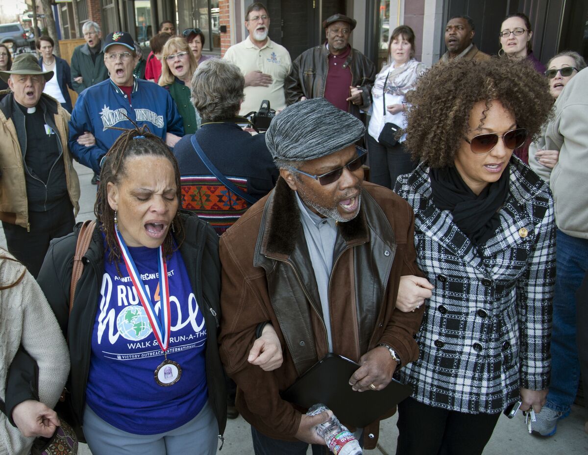 In this March 6 file photo, from left, Della Montgomery-Riggins, Charles Thornton and Rachel Dolezal link arms and sing "We Shall Overcome" at a rally in downtown Spokane, Wash., responding to a racist and threatening package received by Dolezal, the NAACP president.