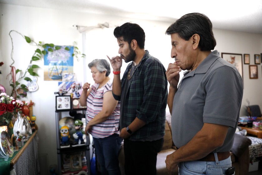 Jonatan Gutierrez, center, with his parents, Pablo Gutierrez and Rocio Urzua, pray on Urzua's late father's birthday.