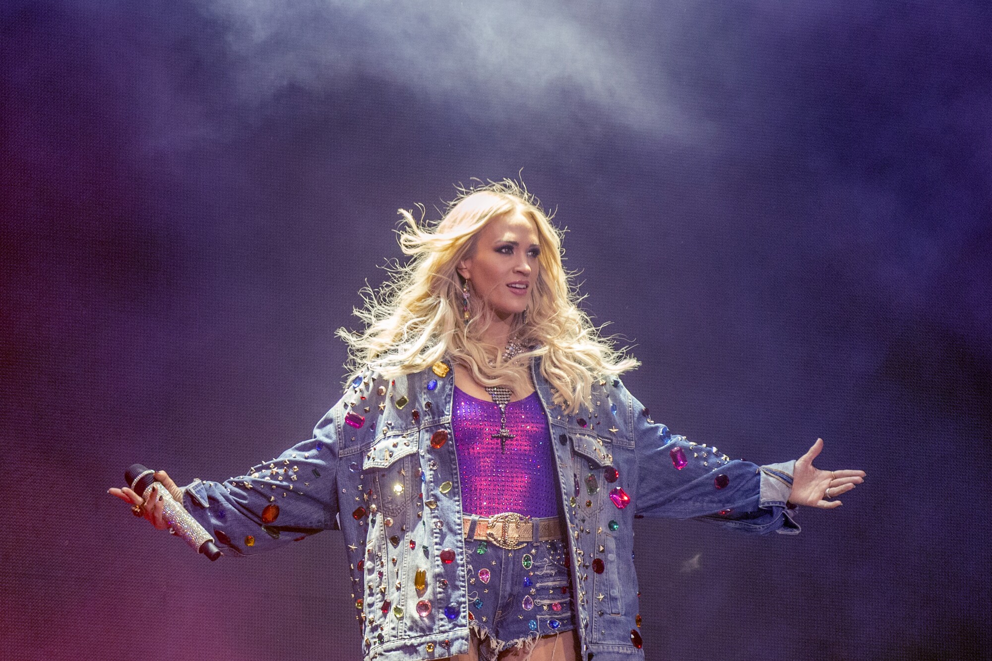 Carrie Underwood holds her arms up to the side as she performs onstage