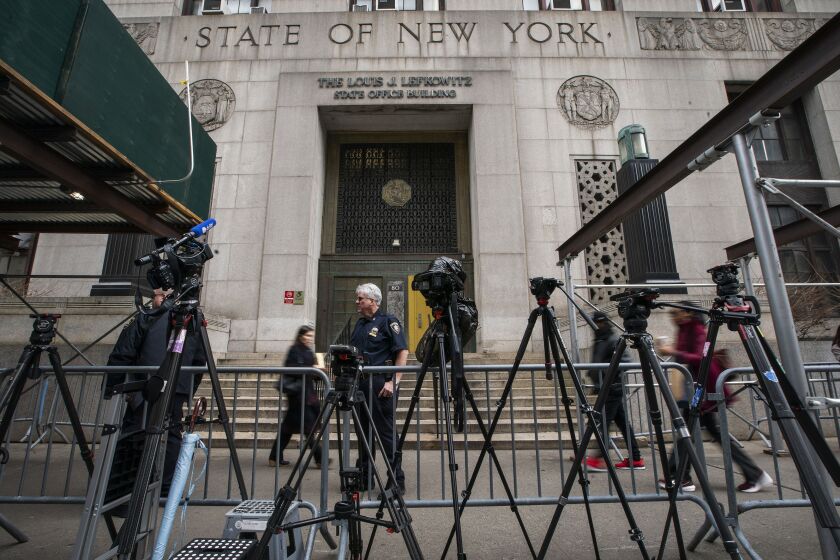 People walk in front the courthouse past cameras and equipment set up by the media ahead of former President Donald Trump's anticipated indictment on Thursday, March 23, 2023, in New York. (AP Photo/Eduardo Munoz Alvarez)