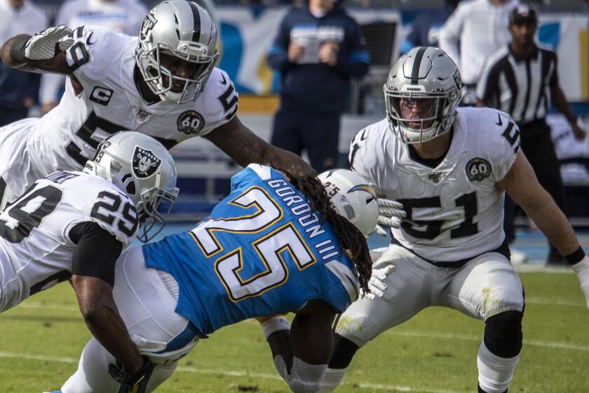 CARSON, CALIF. -- SUNDAY, DECEMBER 22, 2019: Los Angeles Chargers Los Angeles Chargers running back Melvin Gordon (25) is brought down by Oakland Raiders Oakland Raiders free safety Lamarcus Joyner (29) during first quarter of game at Dignity Health Sports Park in Carson, Calif., on on Dec. 22, 2019. (Brian van der Brug / Los Angeles Times)