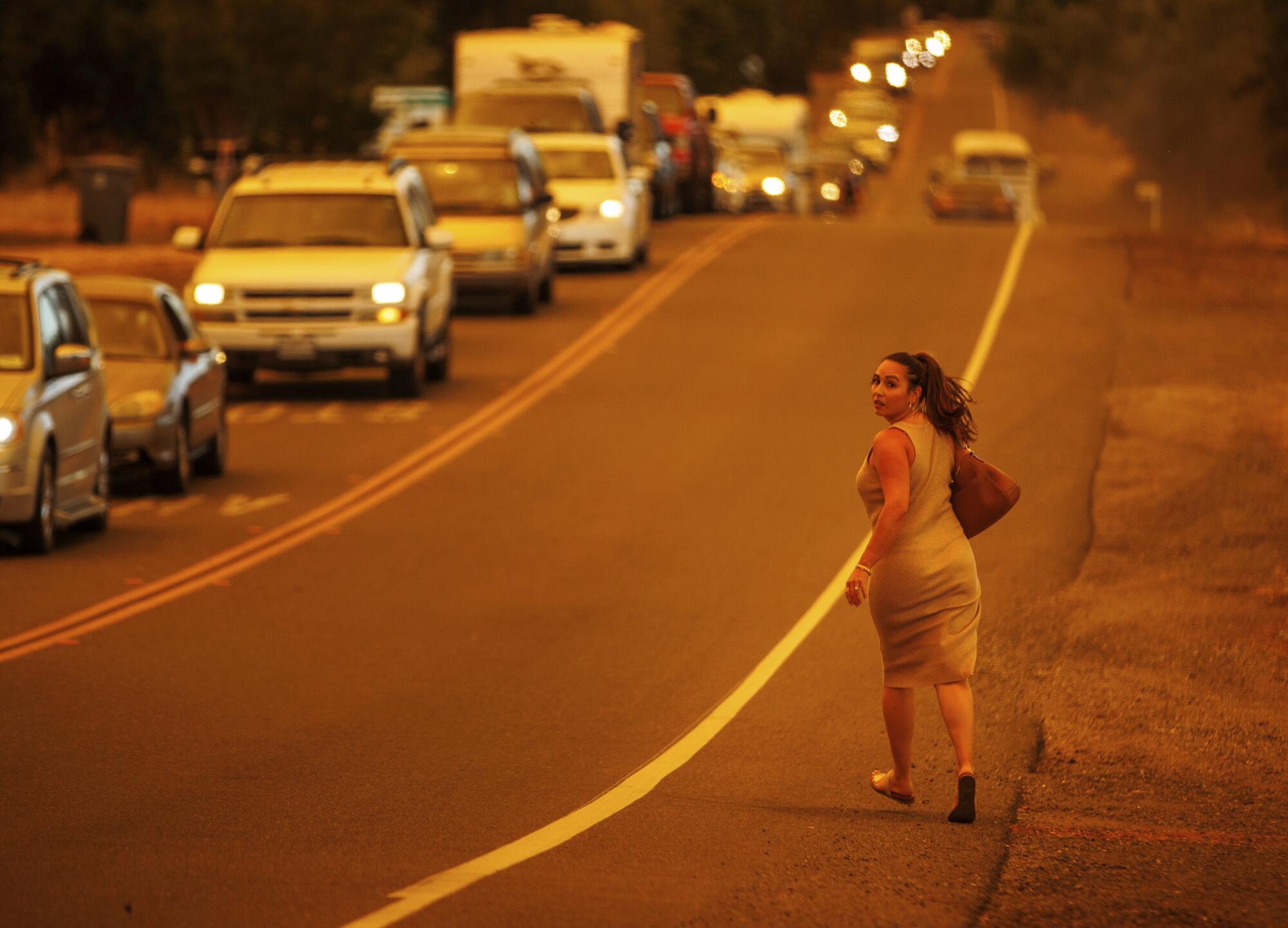 Una mujer corre mientras los autos son evacuados del incendio Thompson en Oroville.