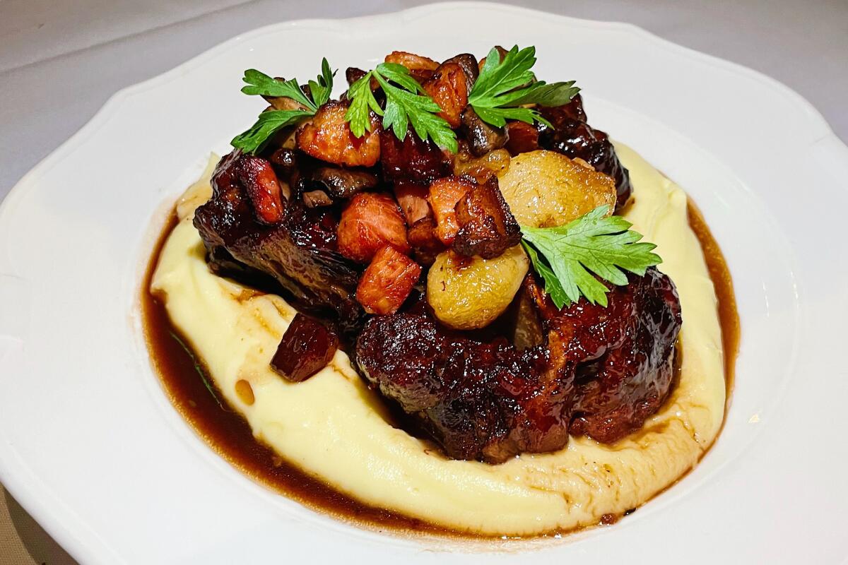 Sauced oxtails sit atop mashed potatoes with carrots, mushroom and parsley