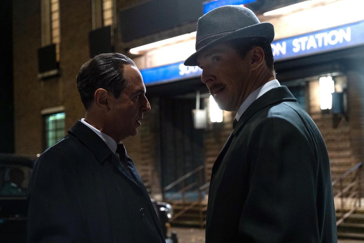 Two men talk in the shadows outside a London Underground station in the movie "The Courier."