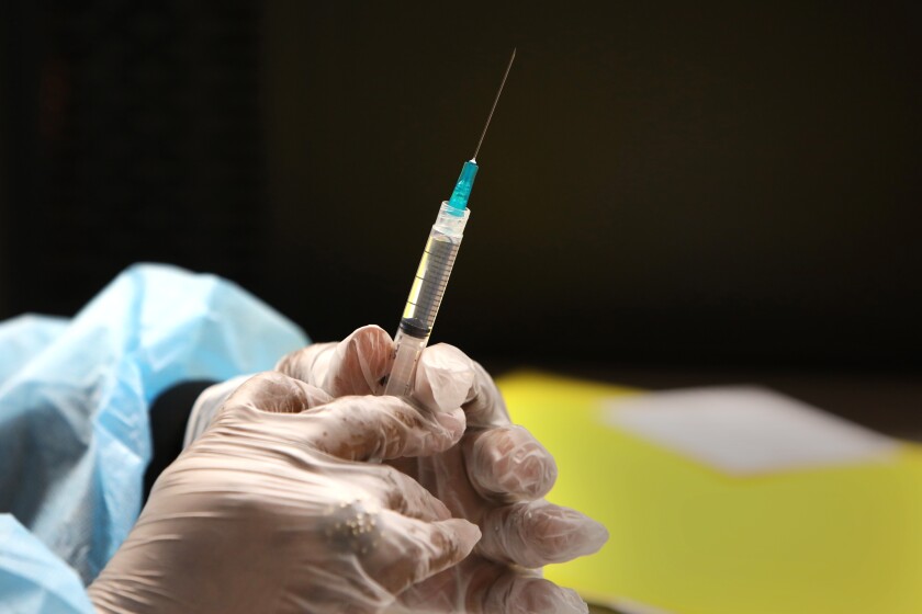 A nurse prepares a syringe of the COVID-19 vaccine.