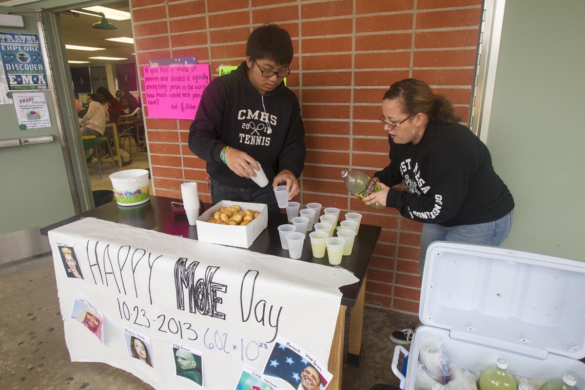 Max Nguyen, 17, left, helps Lee Kelly, the science department chair, set up donut holes and lemonade which Kelly cleverly named donut "moles" and le"mole"ade during a celebration of Mole Day at Costa Mesa High School on Wednesday, October 23. Mole Day is celebrated by chemistry students and chemists on October, 23 from 6:02 am to 6:02 pm which is derived from Avogadro's number 6.02x10^23, defining the number of particles in one mole of substance.
