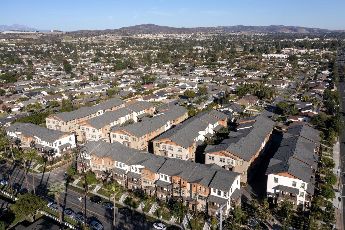 An aerial frame of several rows of apartment buildings near single-family homes.