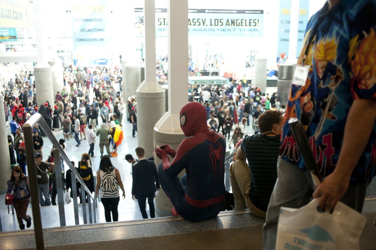 Spider-Man sits at the top of some stairs overlooking a crowd at the L.A. Convention Center.