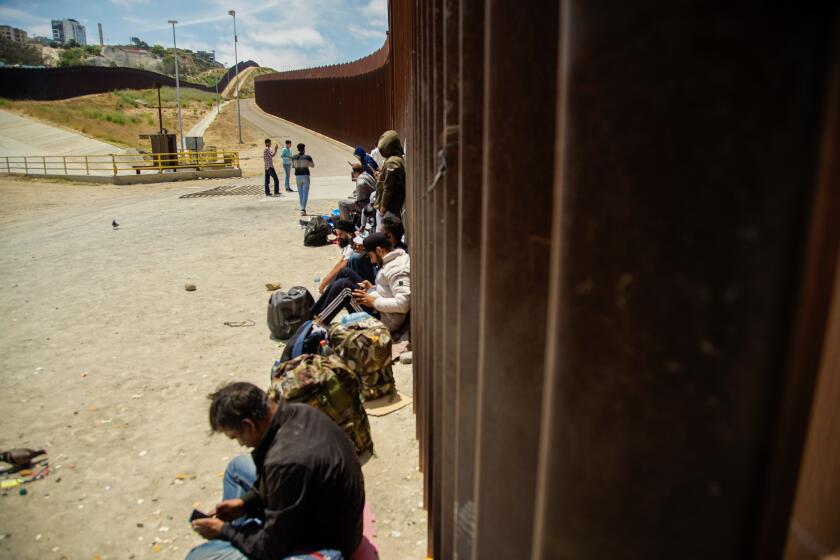 San Diego, California - June 04: Migrants from India seeking asylum wait along the border wall in the Tijuana River Valley on Tuesday, June 4, 2024 in San Diego, California. (Alejandro Tamayo / The San Diego Union-Tribune)