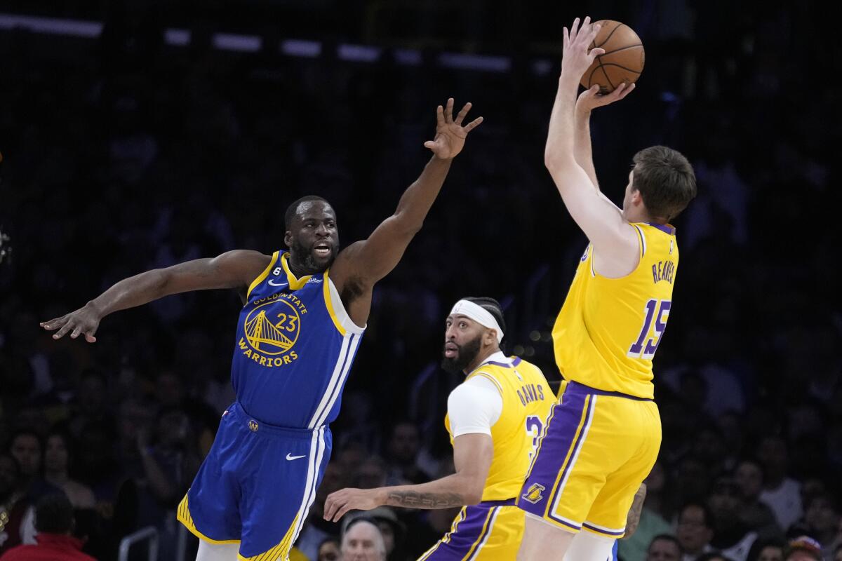 Lakers guard Austin Reaves, right, shoots over the defense of Warriors forward Draymond Green.