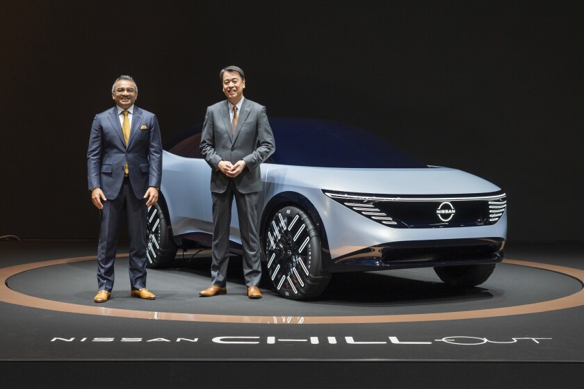 In this photo provided by Nissan Motor Co., Chief Executive Makoto Uchida, right, and COO Ashwani Gupta, left, pose with a Nissan Chill-Out concept car on Nov. 27, 2021. Nissan said Monday, Nov. 29, 2021, it is investing 2 trillion yen ($17.6 billion) over the next five years and developing a cheaper, more powerful battery to boost its electric vehicle lineup. (Nissan Motor Co. via AP)