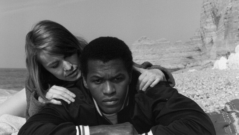 A black-and-white photo of a woman with her hand on the shoulders of a man