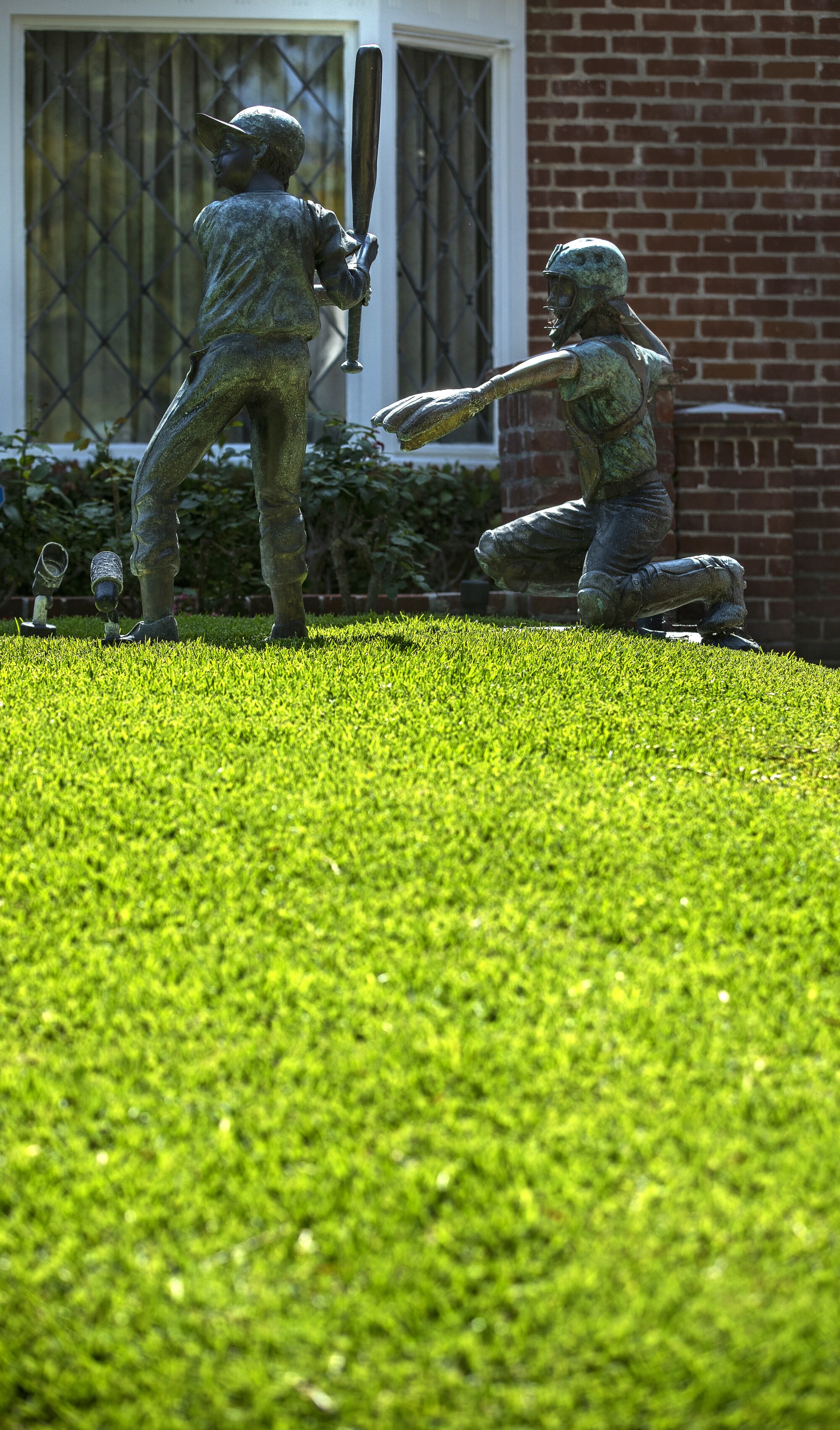 Las estatuas con temas de béisbol y un césped verde son parte del paisaje frente a una casa en Arden Dr. en Beverly Hills. 