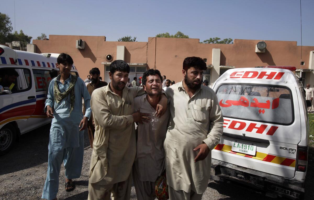 Pakistanis comfort a man mourning the death of a family member in the bombing of a fruit and vegetable market in Islamabad.