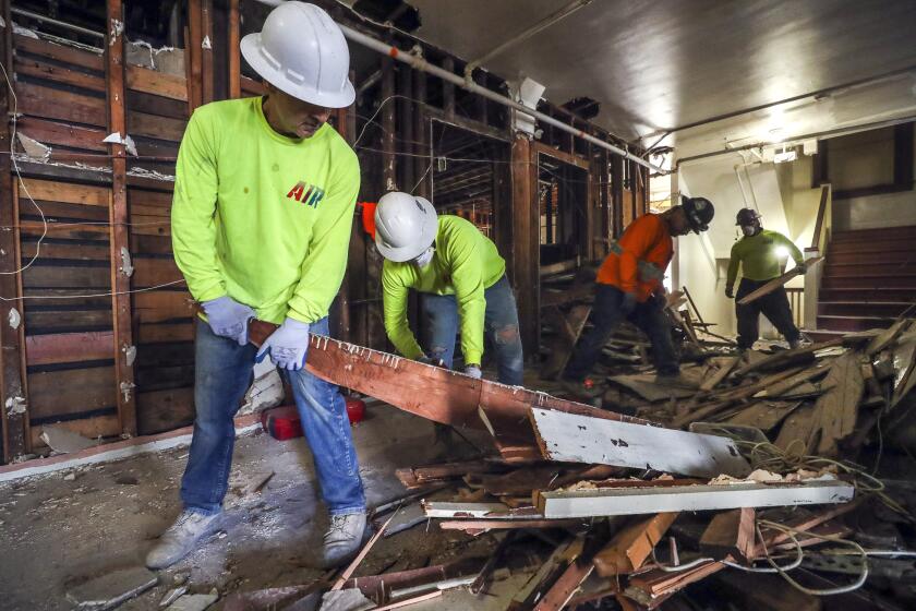 Construction worker Robert Murat, left, holds a piece of wood as Joel Iglesias uses a saw to cut it up as they and other workers do demolition work on the fourth floor of the Plaza Hotel, a SRO (single-room occupancy) hotel that's being converted to a more upscale hotel and hostel, on Thursday, November 15, 2019 in San Diego, California.