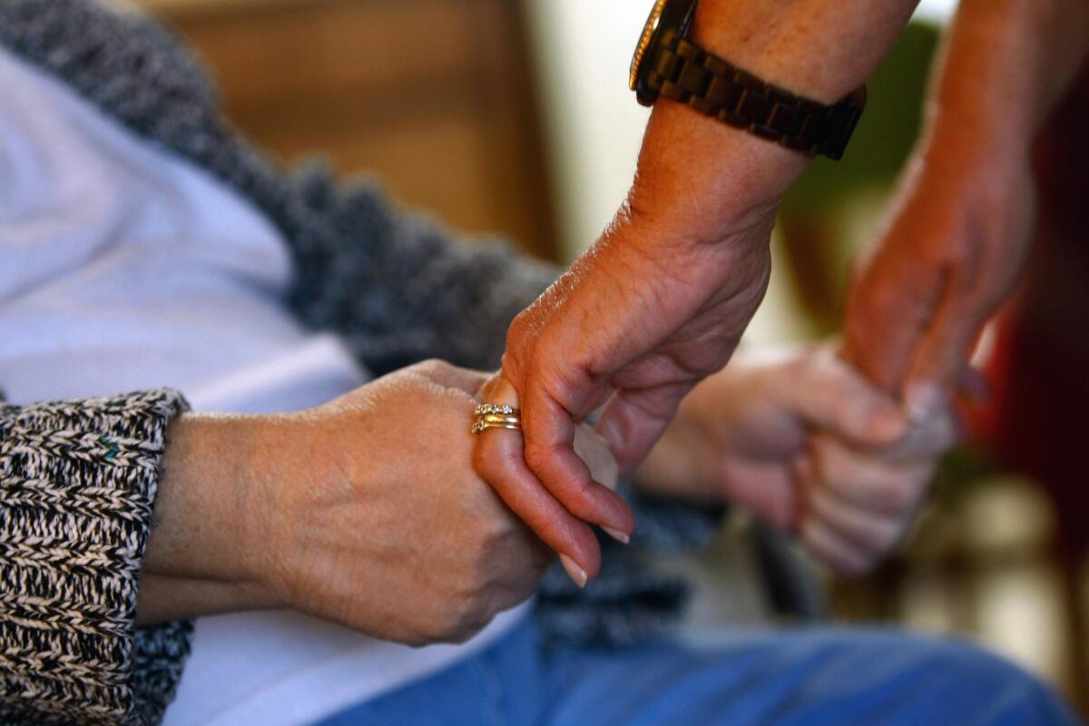 A registered nurse checks the strength of a patient's grip while performing a home visit in Denver, Colo. in 2009.