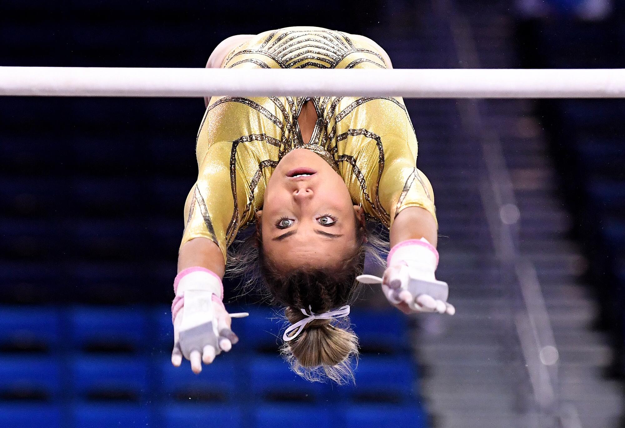 UCLA's Alexis Jeffrey in midair while looking at a bar with her arms in front of her on the uneven bars.