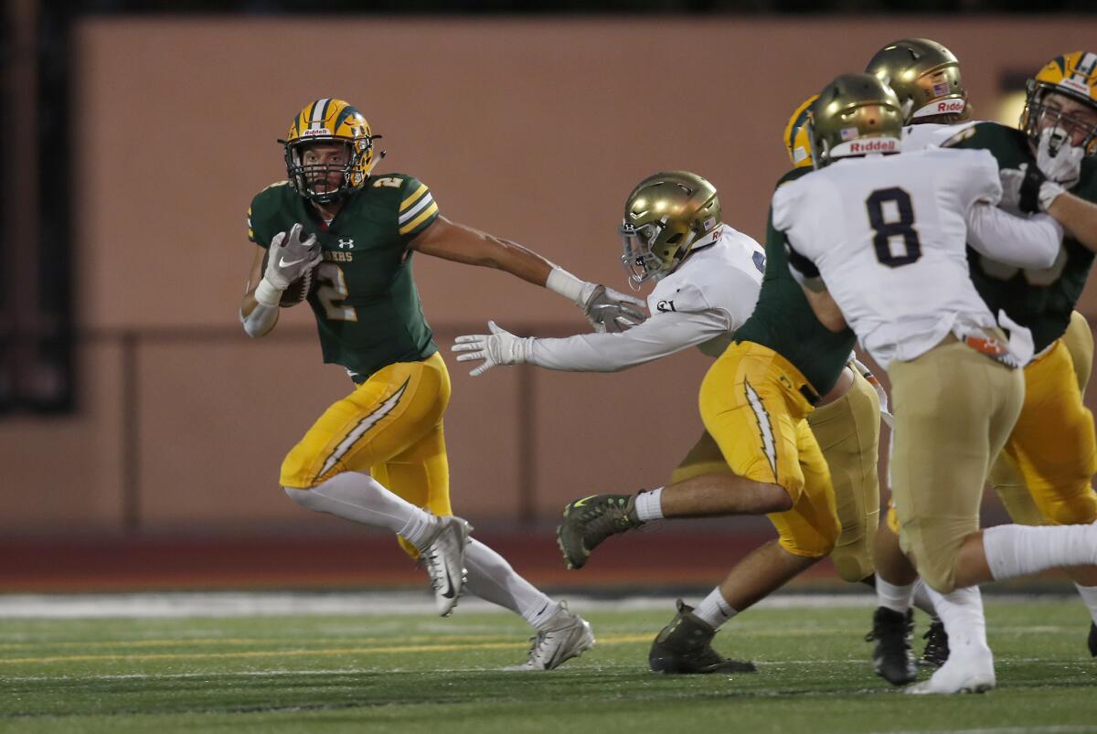 Edison's Mike Walters, left, carries the ball against San Juan Hills during the first half of a nonleague game at Huntington Beach High on Sept. 13.